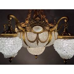 an ornate chandelier with three lights hanging from it's sides and gold trimmings