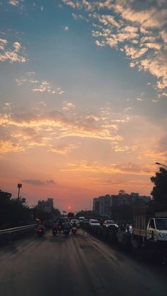 the sun is setting behind some cars on the road