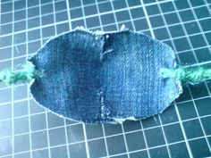 an old pair of jeans that has been torn and is laying on the ground with some green thread