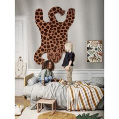 two children are sitting on a bed in front of a large animal head wall hanging