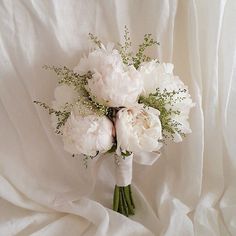 a bridal bouquet with white peonies and baby's breath on a bed