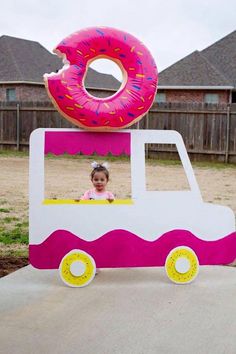 a child's photo taken in front of a fake doughnut truck with a donut on top