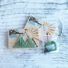 two pieces of string art sitting on top of a wooden table