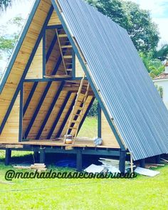 a - frame house built into the grass with stairs leading up to it's roof