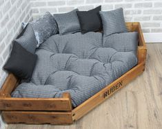 a futon bed made out of wooden pallets with pillows on the top and bottom