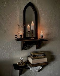 some books and candles on a shelf in front of a mirror with a candle holder