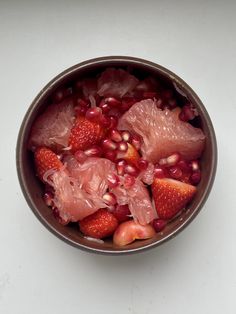 a bowl filled with fruit sitting on top of a white counter next to a knife