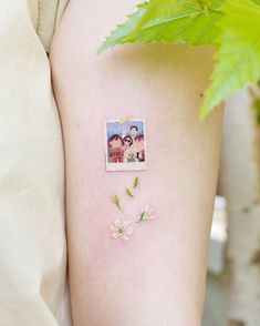 a woman's arm with flowers on it and an image of two people in the background