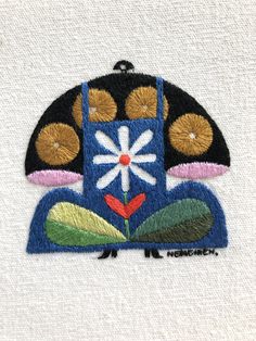 an embroidered patch with flowers and leaves on it