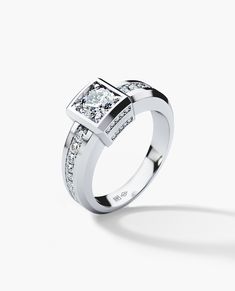 a white gold ring with two square diamonds on the side and one diamond set in the middle