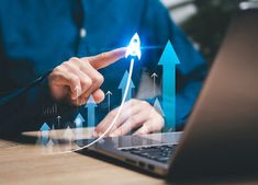 a man pointing to an upward arrow on his laptop