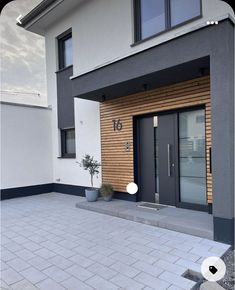 the front entrance to a modern home with two doors and brick walkway leading up to it