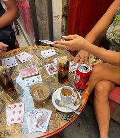 people sitting around a table with playing cards and drinks