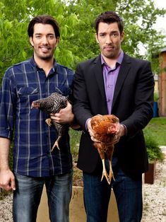 two men standing next to each other holding chickens