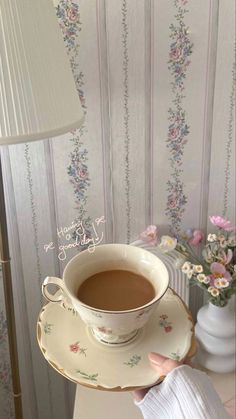 a cup of coffee sitting on top of a saucer next to a white lamp