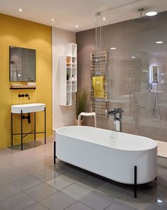 a bath tub sitting next to a white sink in a bathroom with yellow accents on the walls