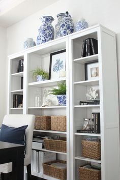 a white bookcase with blue and white vases on top of it in a living room