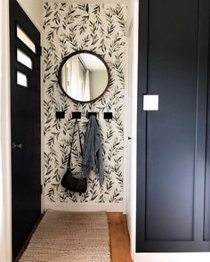 a hallway with a mirror, coat rack and rug