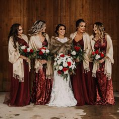 a group of women standing next to each other in front of a wooden wall holding bouquets