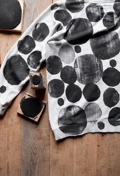 a black and white polka dot sweater on top of a wooden floor next to some pieces of wood