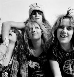 an old black and white photo of four people in a room with clothes hanging on the wall