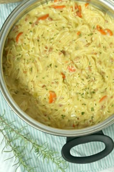 a pot filled with noodles and carrots on top of a table