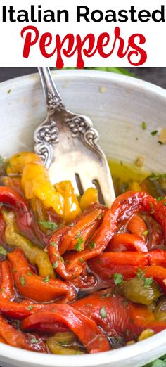 a white bowl filled with red and yellow peppers next to a silver spoon on top of a table