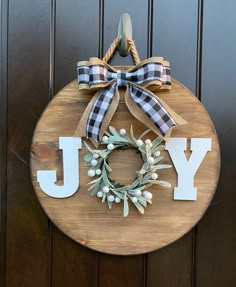 a wooden sign with the word joy hanging on it's side and a wreath