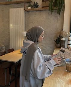 a woman sitting at a table reading a newspaper