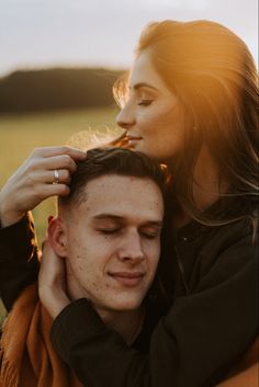 a man and woman standing next to each other in a field with the sun shining on them