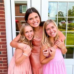 three girls are posing for the camera in front of a door with their arms around each other