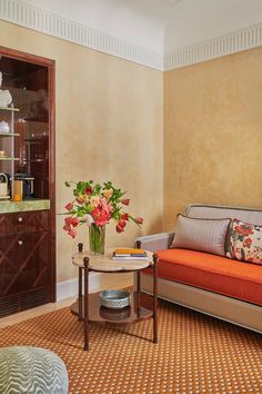 a living room filled with furniture and flowers in a vase on top of a table