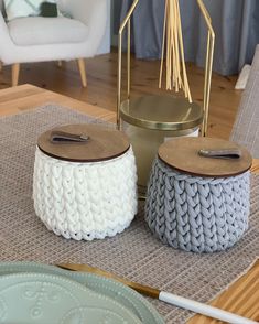 two knitted stools sitting on top of a wooden table next to a white chair