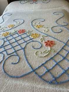 the bed is made up with crocheted bedspread and flowers on it