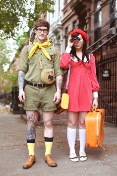 a man and woman dressed in costumes standing next to each other on the street with luggage