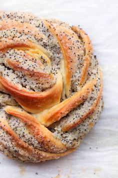 a close up of some bread on a white table cloth with poppy seed sprinkles