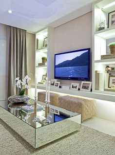 a living room filled with furniture and a flat screen tv mounted on a wall above a glass coffee table