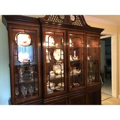 a wooden china cabinet with glass doors and plates on it