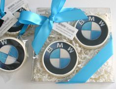 two decorated cookies in the shape of bmw emblems with blue ribbon and bow on top