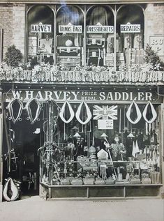 an old black and white photo of a store front with many items on display in the window