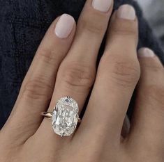 a woman's hand with a ring on her finger and an oval diamond in the middle