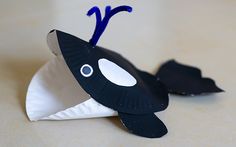 a paper plate with a black and white fish on it's side, sitting on a table