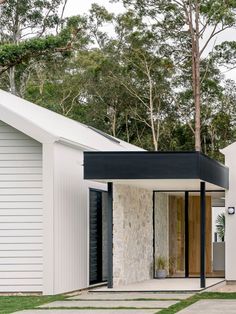 a white house with black shutters on the front door and side entry to it