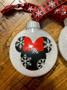 two mickey mouse christmas ornament ornaments on a wooden table with a red ribbon