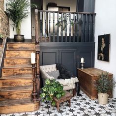 a living room filled with furniture next to a stair case and potted greenery