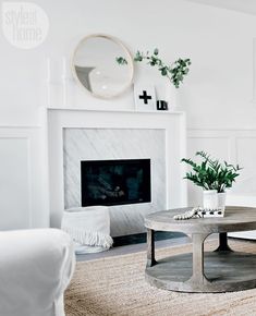 a living room with a white couch, coffee table and fireplace