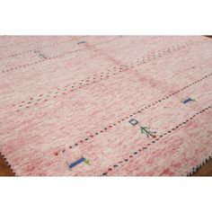 a pink rug with different designs on the top and bottom, sitting on a wooden floor