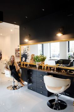 a woman sitting on a chair in front of a desk with a mirror above it