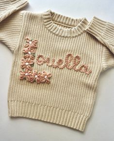 a knitted sweater with the word love written on it and flowers embroidered on the front