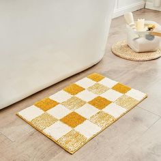 a yellow and white rug sitting on the floor next to a bath tub